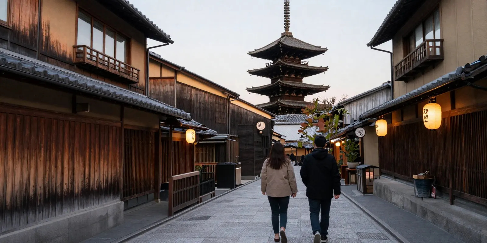 A quiet old-town street in Kyoto at dusk with lanterns and a pagoda