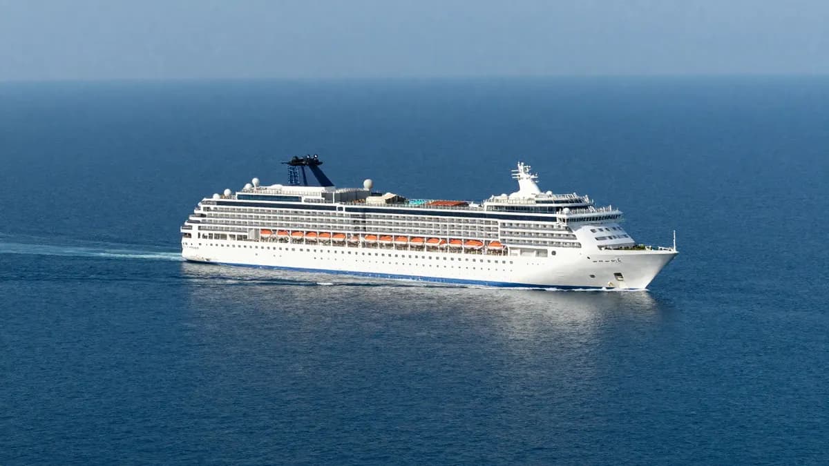 A large white cruise ship sailing on open blue sea far from land