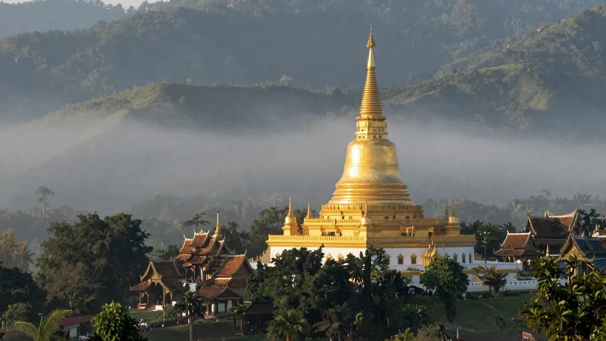 A golden temple among misty mountains in northern Thailand at sunrise