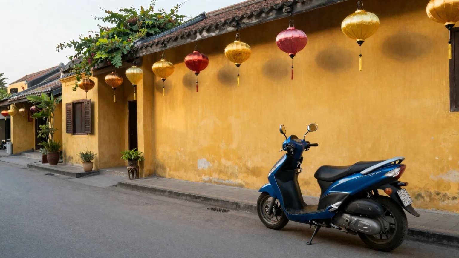 A scooter parked on a quiet yellow-walled street in Hoi An old town under hanging silk lanterns